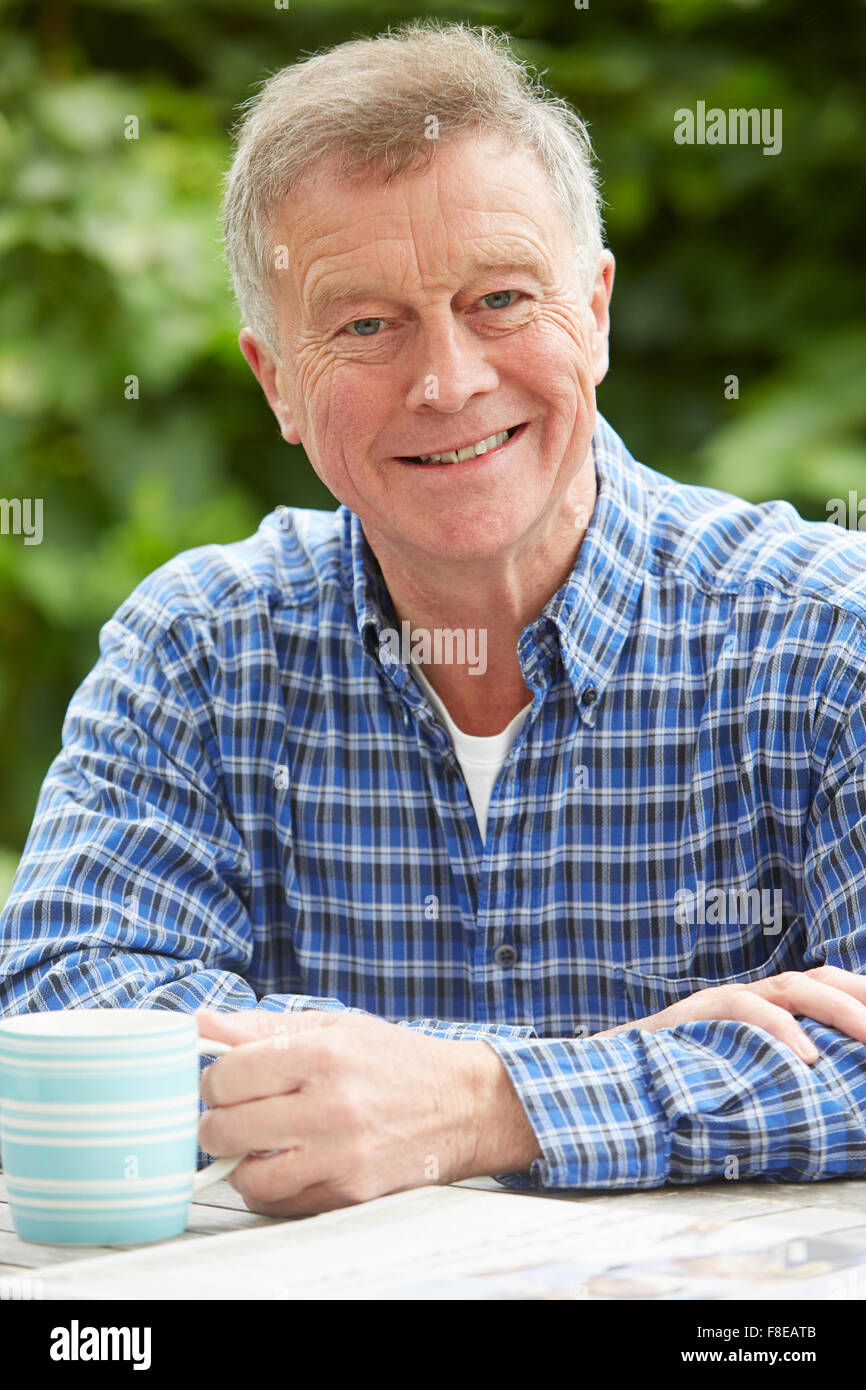 Senior Woman Relaxing In jardin avec un verre et un journal Banque D'Images