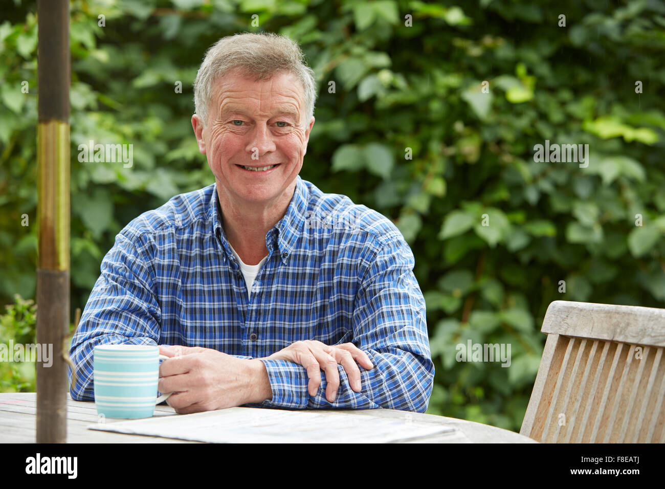 Senior Woman Relaxing In jardin avec un verre et un journal Banque D'Images