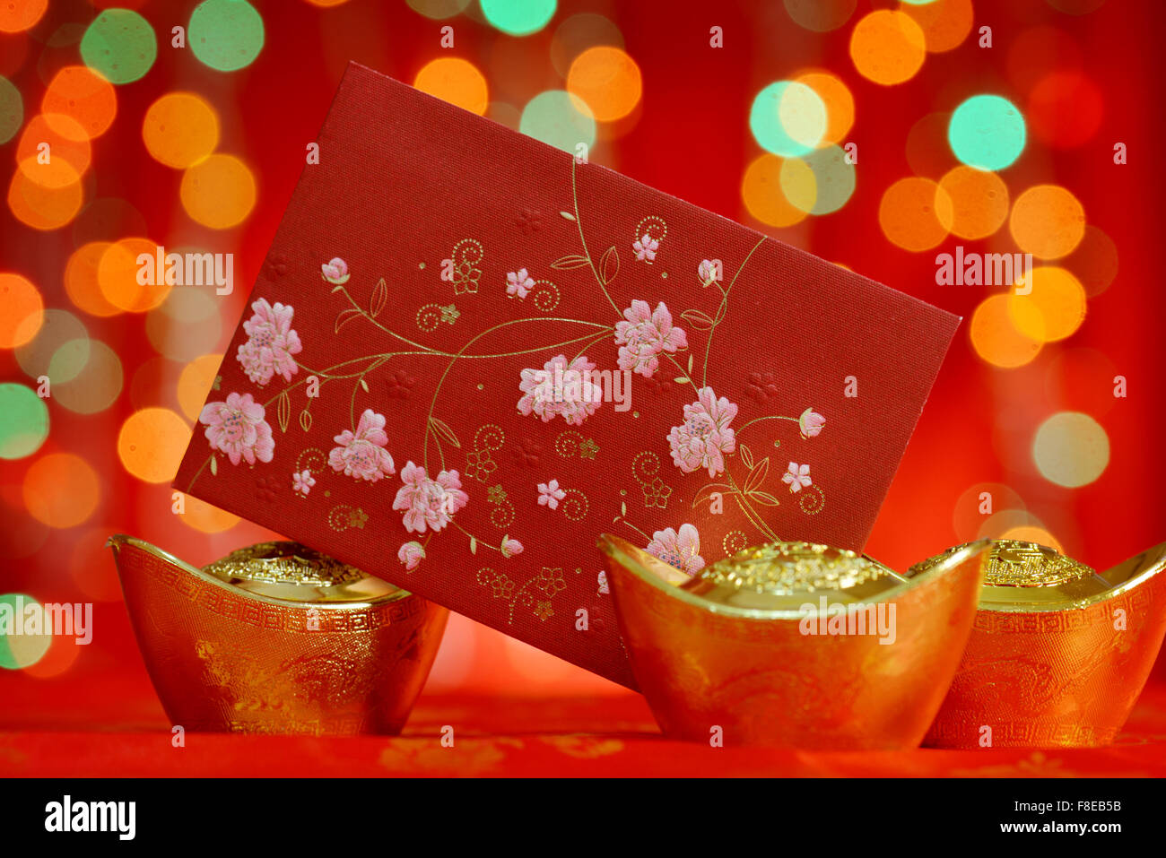 Décorations du nouvel an chinois, paquet rouge et or lingots sur red glitter. Banque D'Images