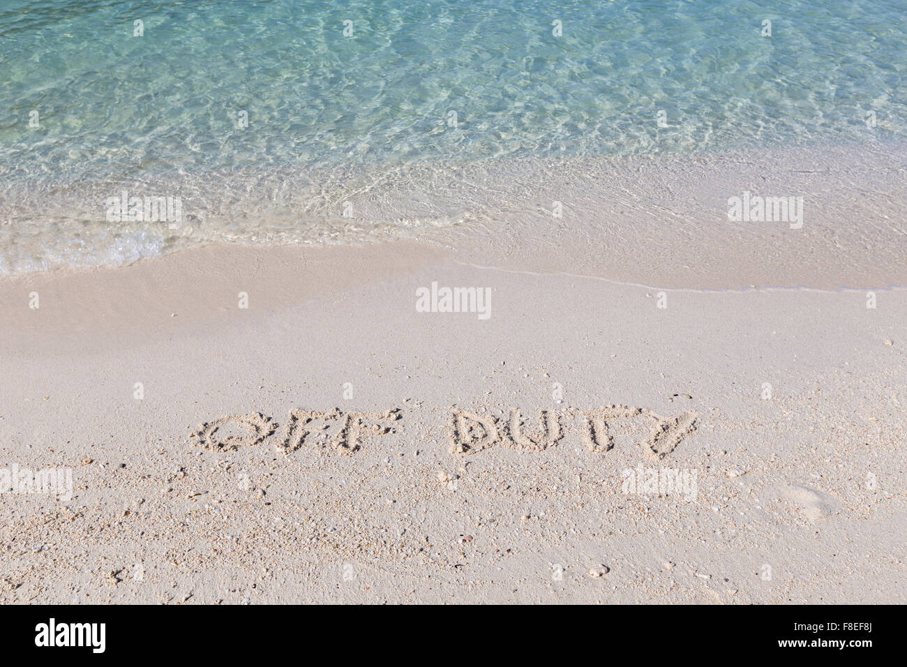 Hors travail écrit dans le sable humide sur une plage tropicale en Thaïlande Banque D'Images