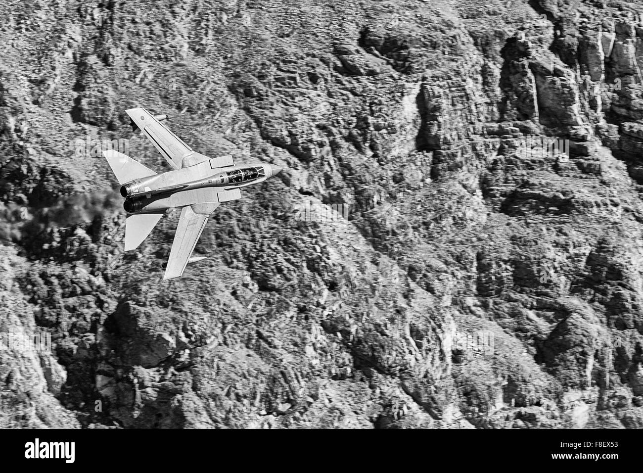 Photo en noir et blanc d'Un avion de chasse Tornado GR4 de la Royal Air Force volant à bas niveau à travers Une vallée du désert. Banque D'Images