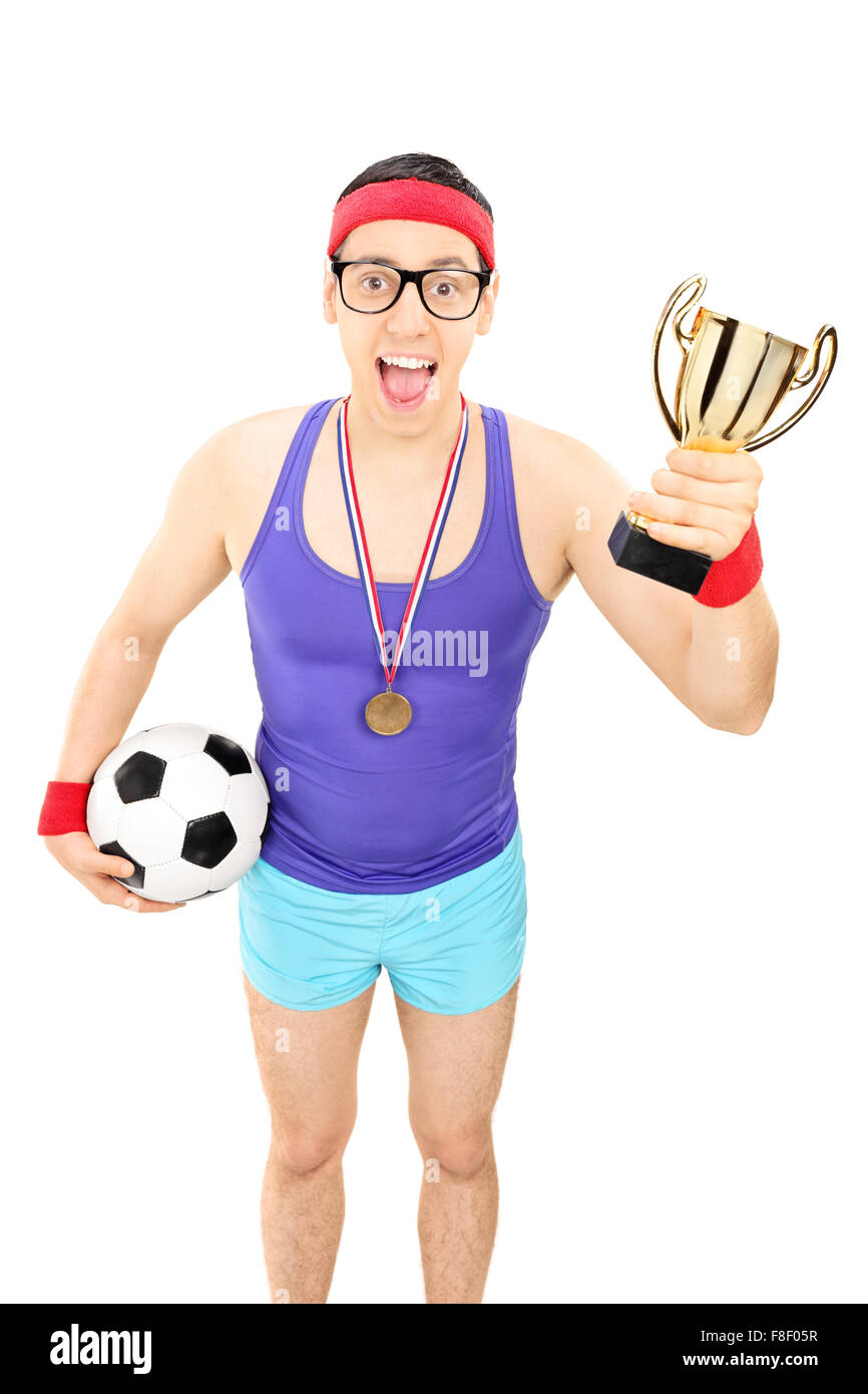 Shot vertical d'un joueur de football nerdy tient un trophée et une médaille portant isolé sur fond blanc Banque D'Images