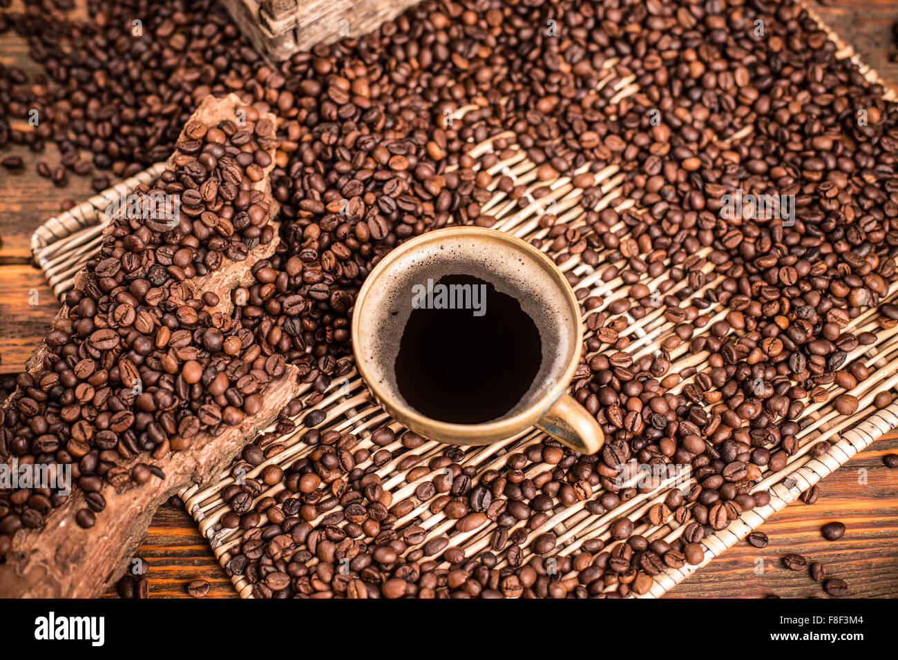 Tasse de café et café en grains éparpillés sur le plateau en osier Banque D'Images