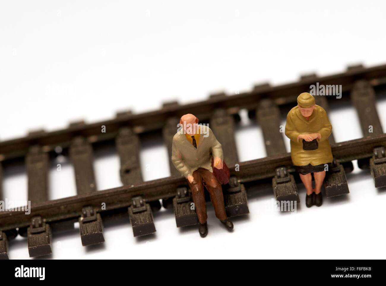 2 pensionnés miniature assis sur modèle réduit de chemin de fer. Concept en voie de retraite Banque D'Images