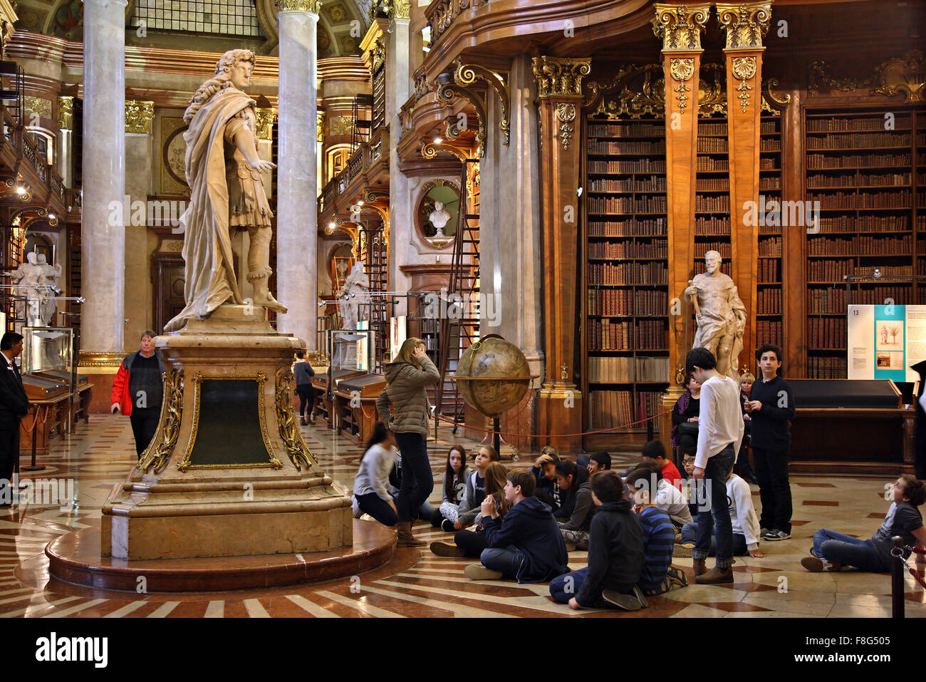 Groupe d'élèves dans le Grand Hall de la Bibliothèque nationale ('Nationalbibliothek Prunksaal) de Vienne, Autriche. Banque D'Images