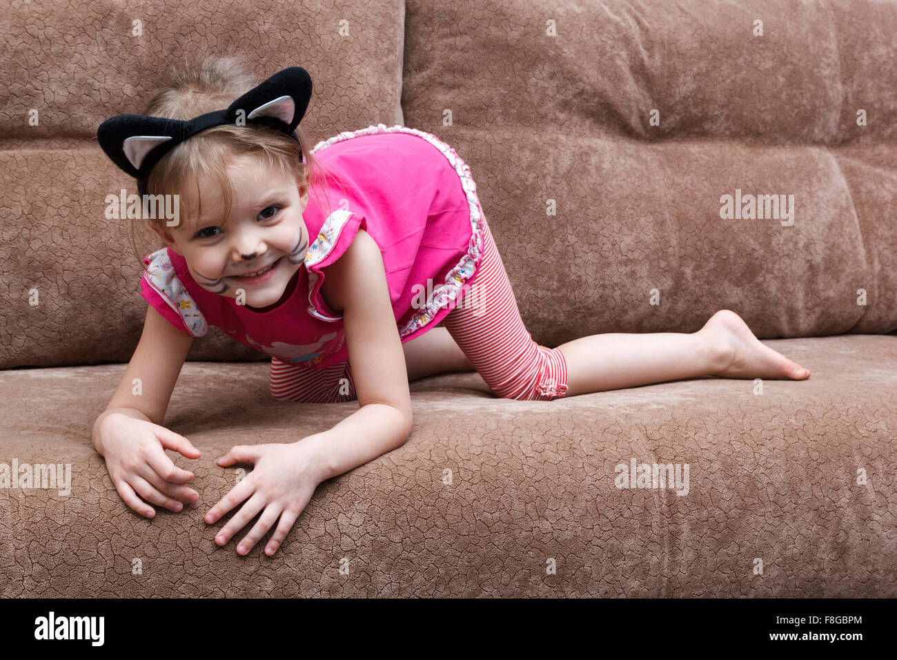 Little girl with cat face painting on a couch Banque D'Images