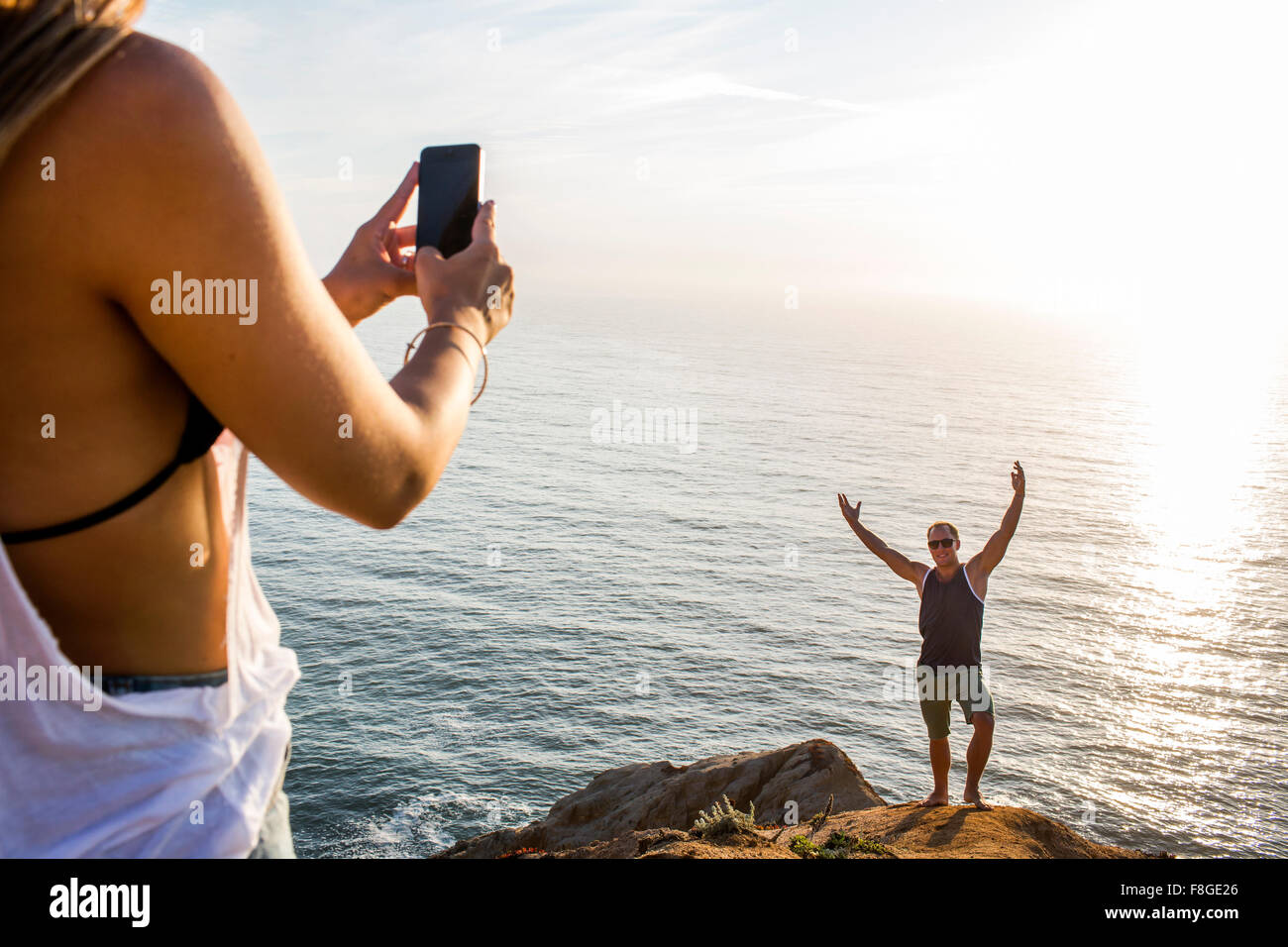 Caucasian man photographing petite amie sur falaise Banque D'Images
