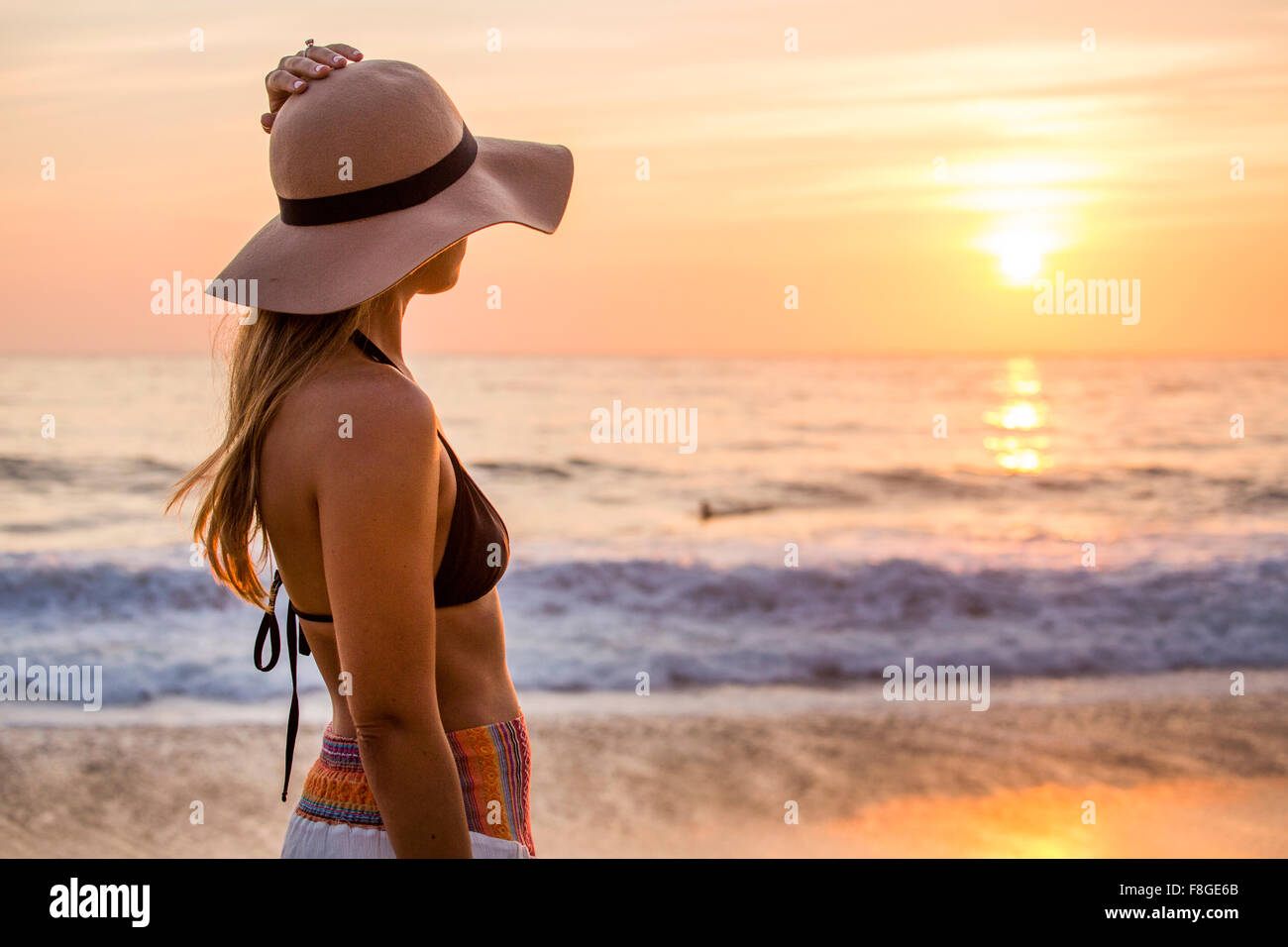 Caucasian woman admiring coucher du soleil et l'océan Banque D'Images