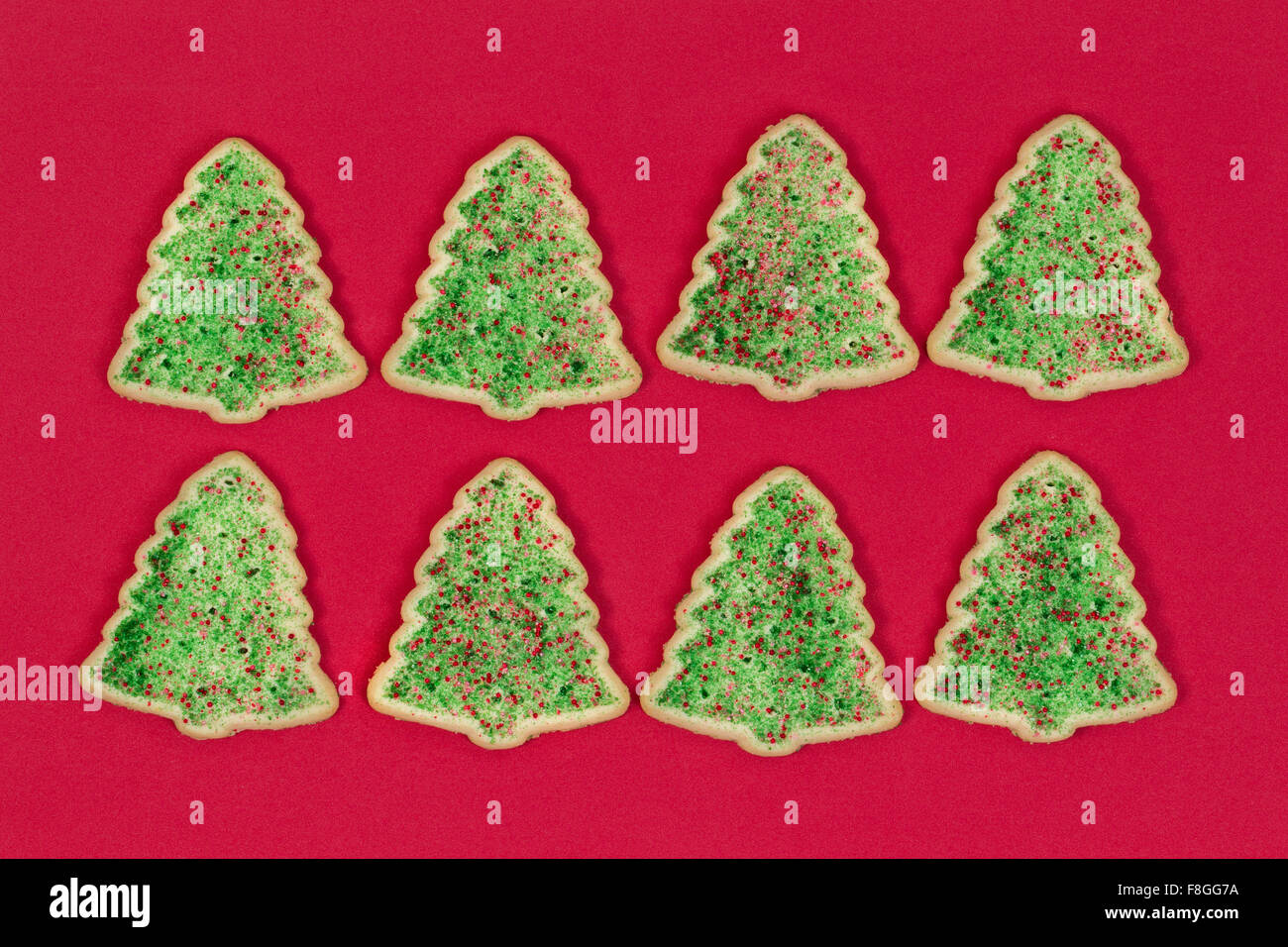 Les cookies en forme d'arbre de Noël organisé sur fond rouge. Banque D'Images