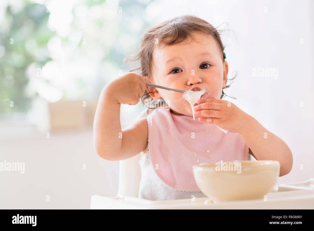 Mixed Race baby girl eating yoghurt Banque D'Images