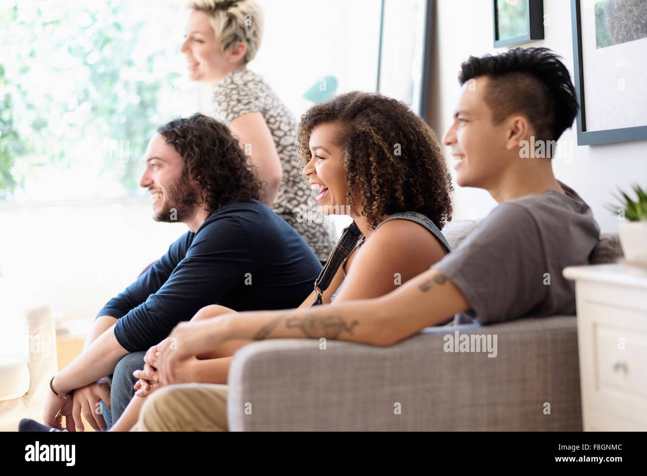 Friends watching television on sofa Banque D'Images