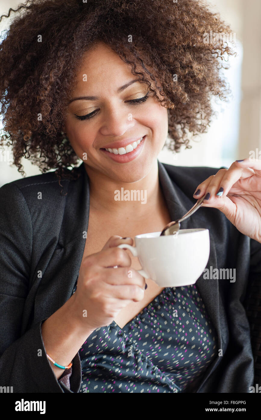 Mixed Race businesswoman drinking cup of coffee Banque D'Images