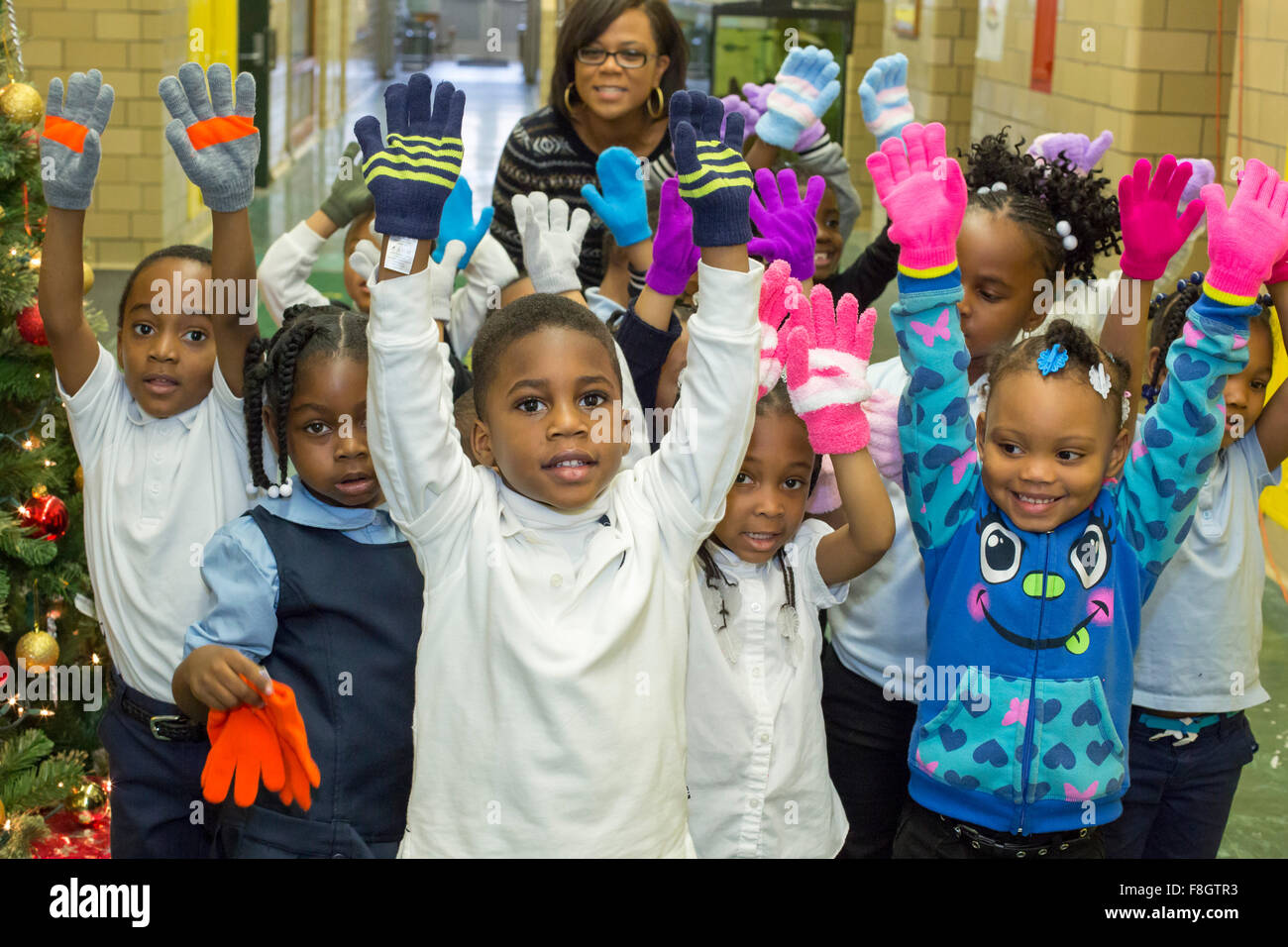 Detroit, Michigan, USA. 9 décembre 2015. Les enfants à l'école élémentaire Dossin montrer les mitaines qu'ils ont reçu d'un organisme de bienfaisance appelé mitaines mitaines pour Detroit. L'organisme distribue des mitaines pour 26 000 élèves du primaire des écoles publiques de Detroit ; la plupart ont été donnés par les employés de Fiat Chrysler Automobiles. Crédit : Jim West/Alamy Live News Banque D'Images