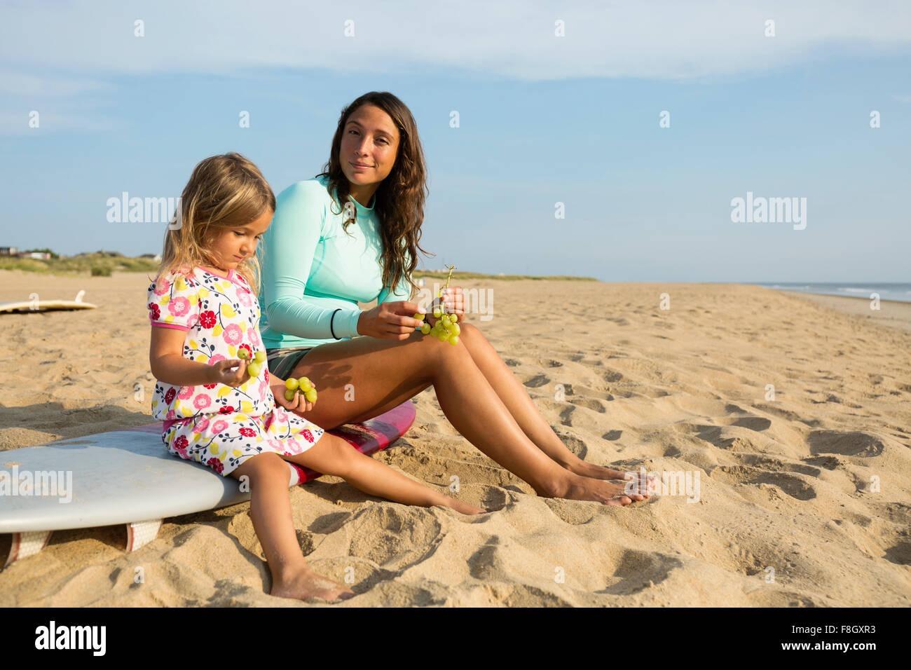 Mother and Daughter eating grapes on beach Banque D'Images