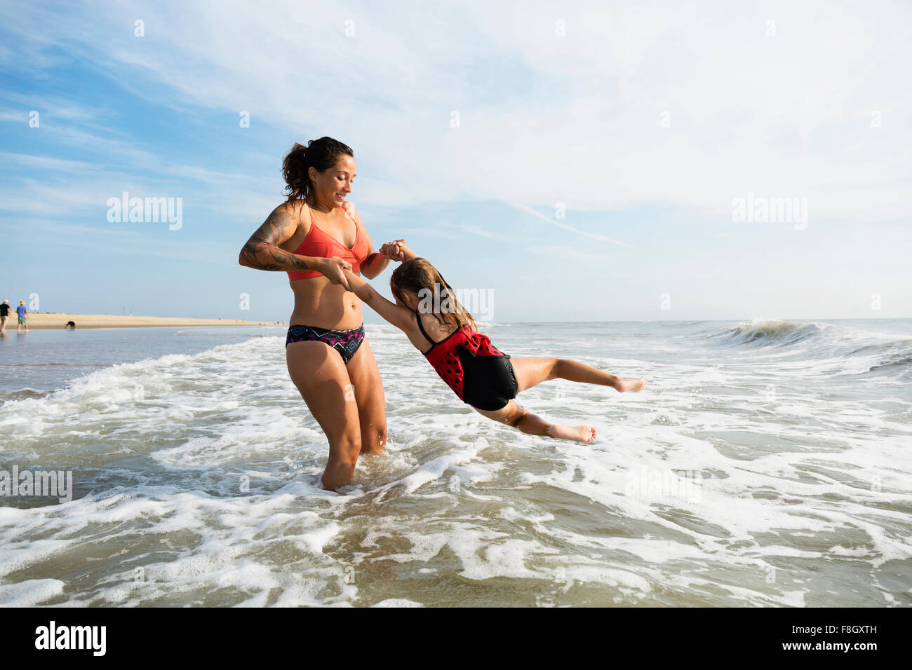 Mère et fille jouer dans les vagues sur la plage Banque D'Images