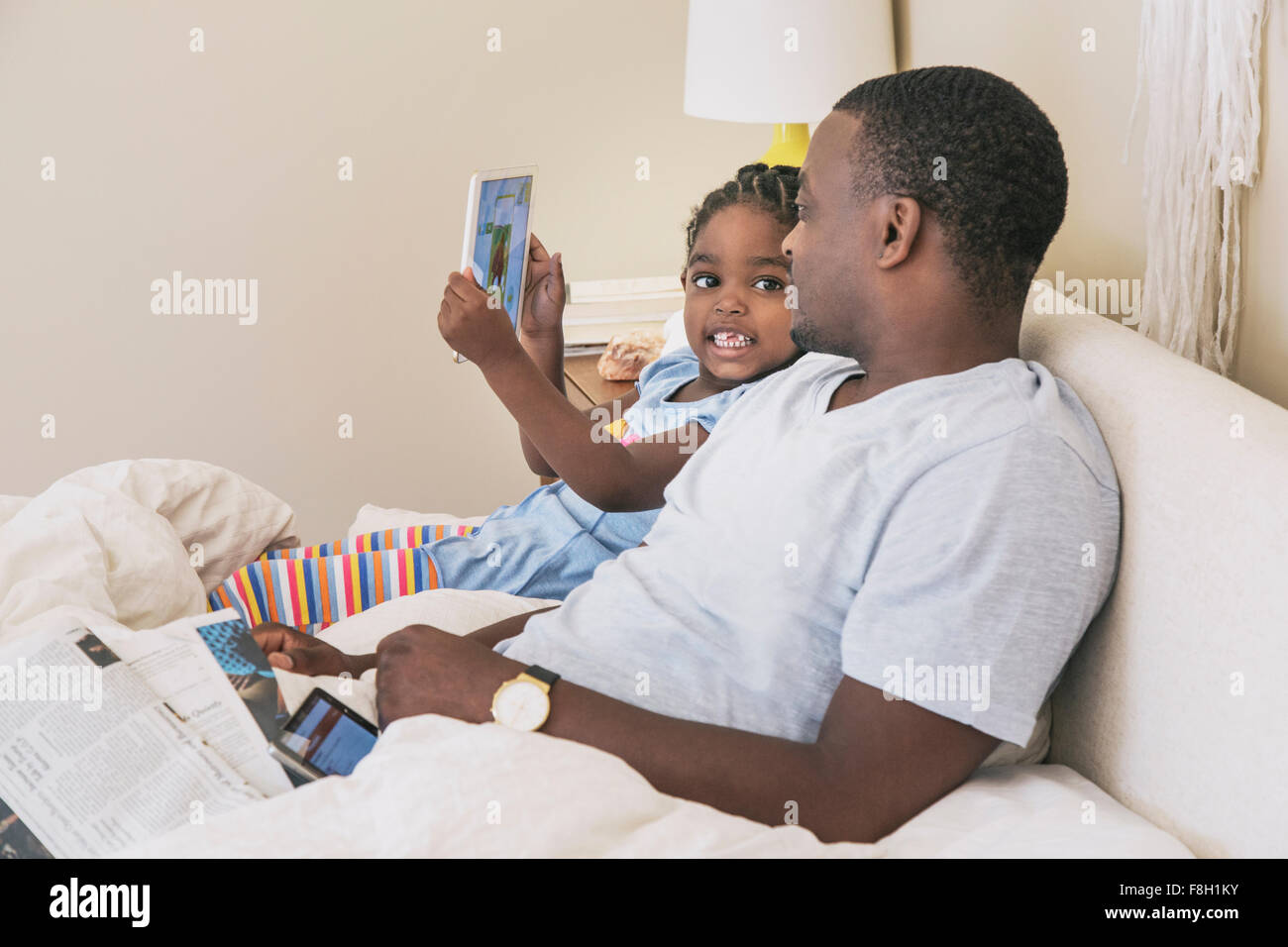African American father and daughter sitting on bed Banque D'Images