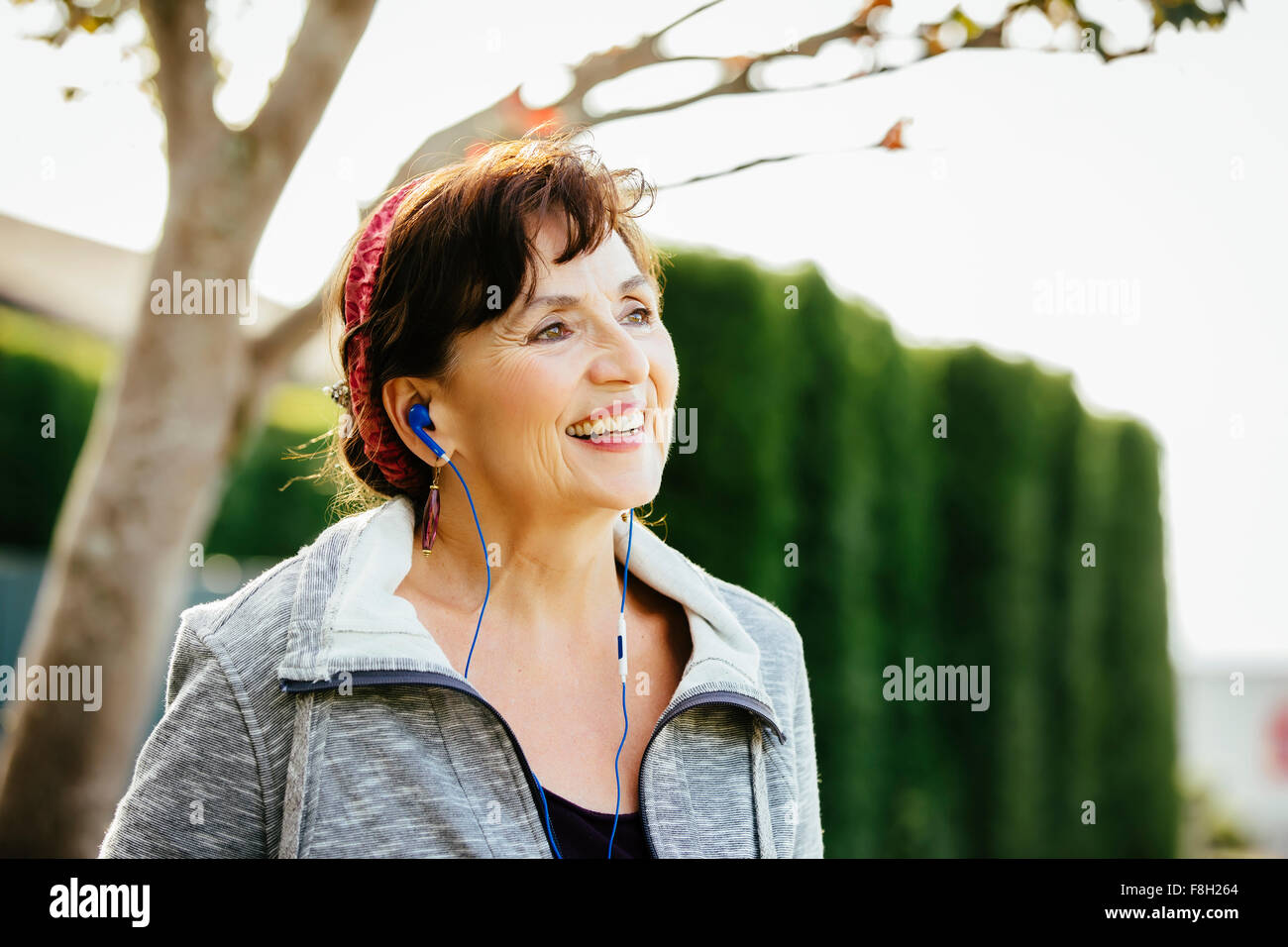 Caucasian woman l'écoute de l'extérieur des écouteurs Banque D'Images