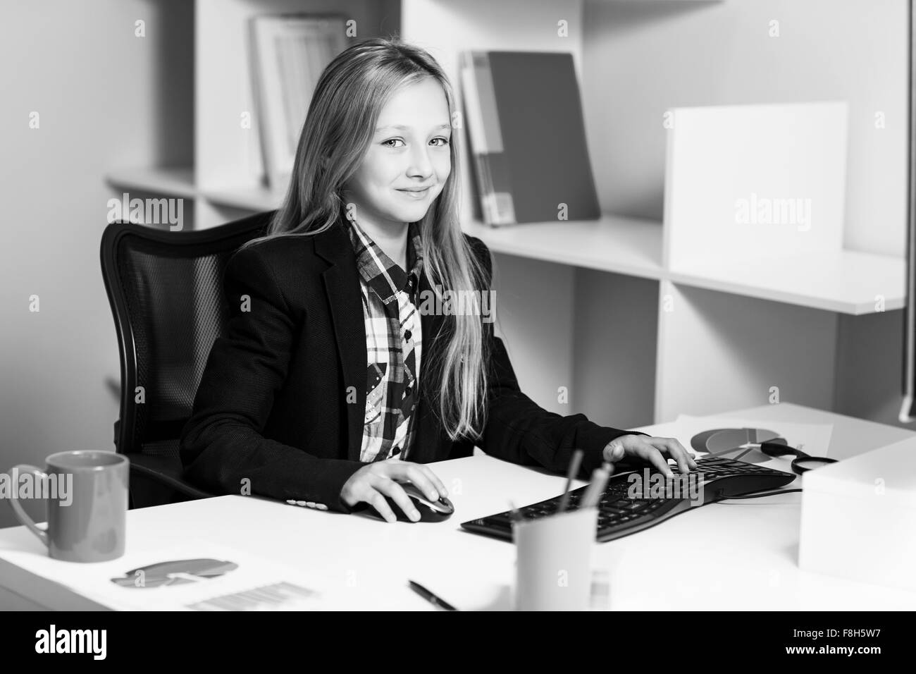 Petite fille comme femme d'affaires à la table Banque D'Images