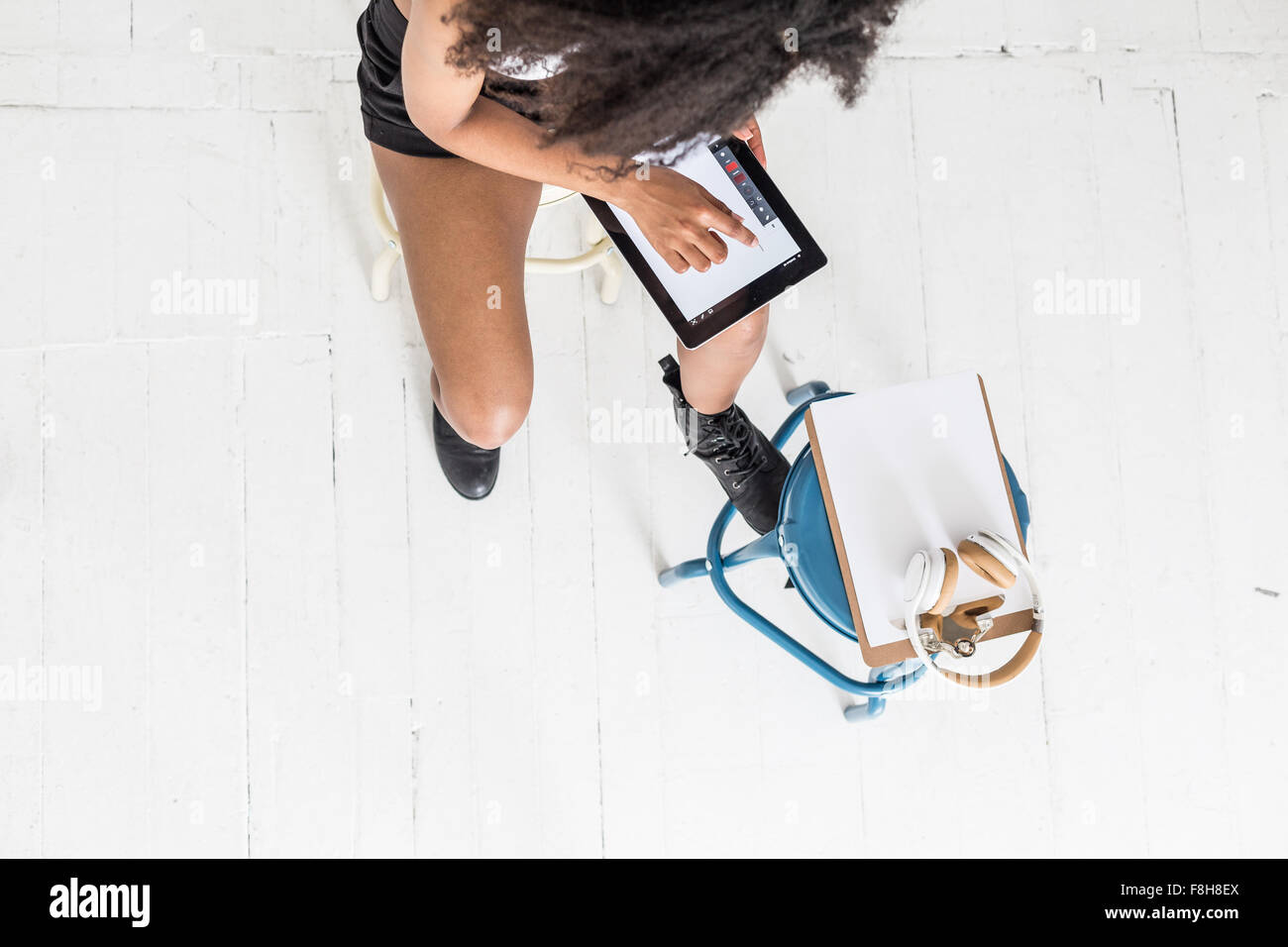 Une jeune femme afro-américaine à l'aide d'un comprimé ou de l'iPad dans un paramètre de type studio Banque D'Images