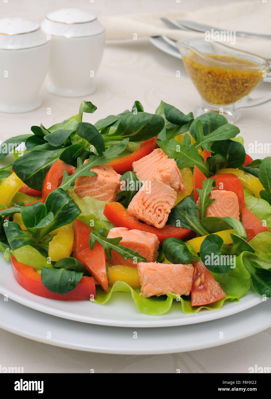 Salade de légumes avec des tranches de saumon, les racines, la roquette, les tomates et poivrons, assaisonné de sauce moutarde au curry Banque D'Images