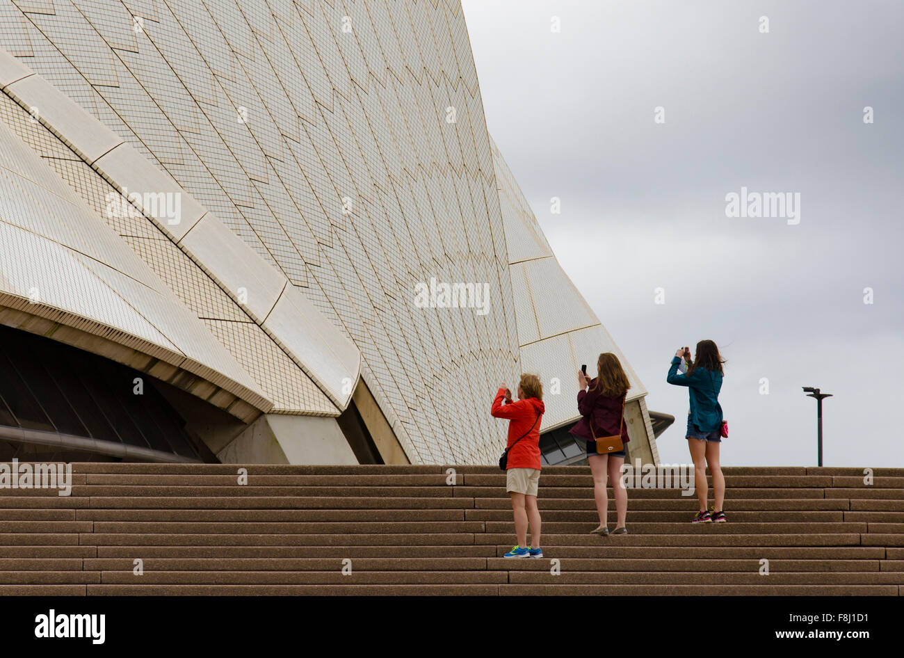 Trois femmes dans une ligne utilisant des iPhones pour photographier l'Opéra de Sydney en Australie Banque D'Images