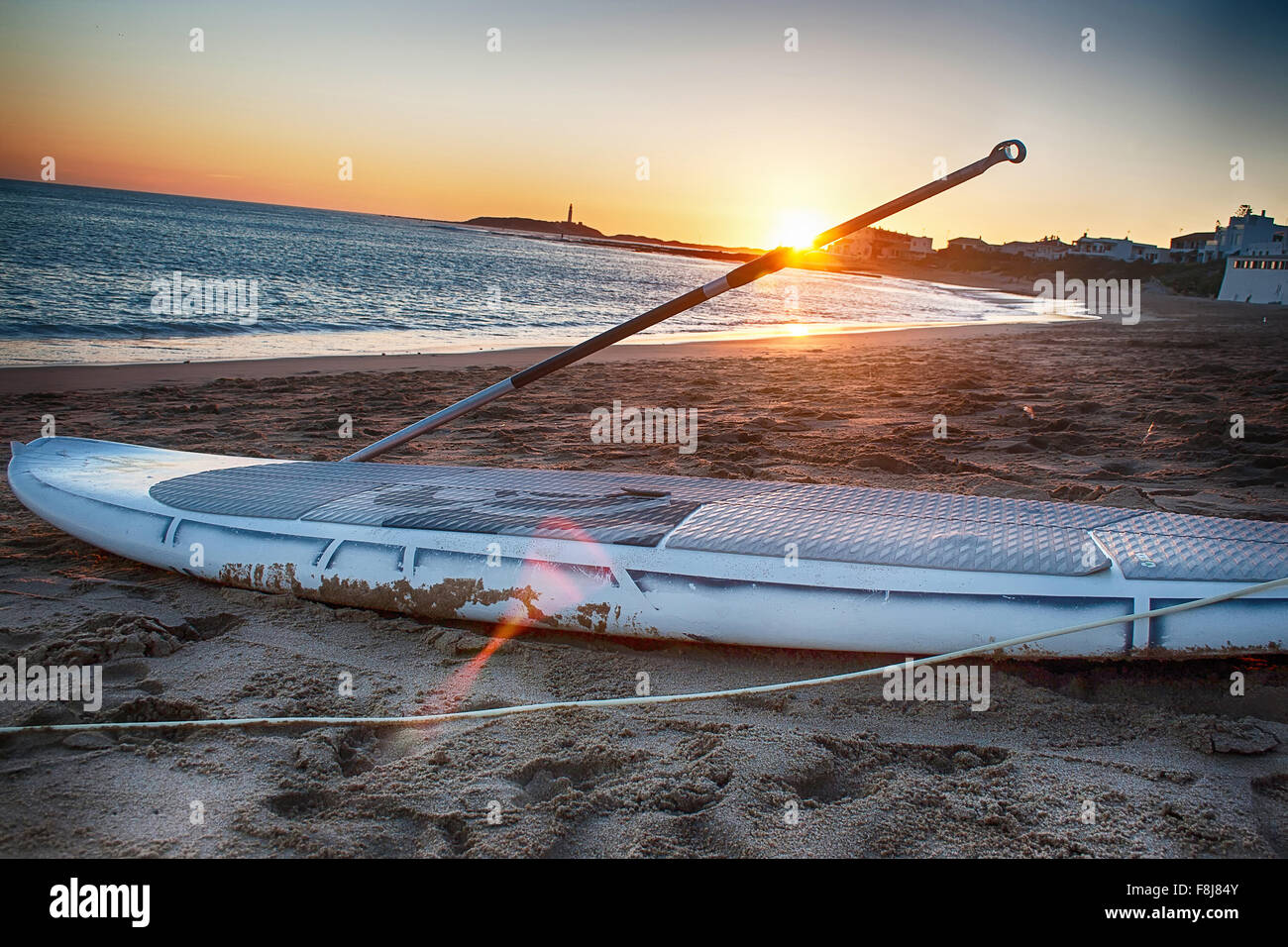 Paddle board sur le sable au coucher du soleil. Banque D'Images