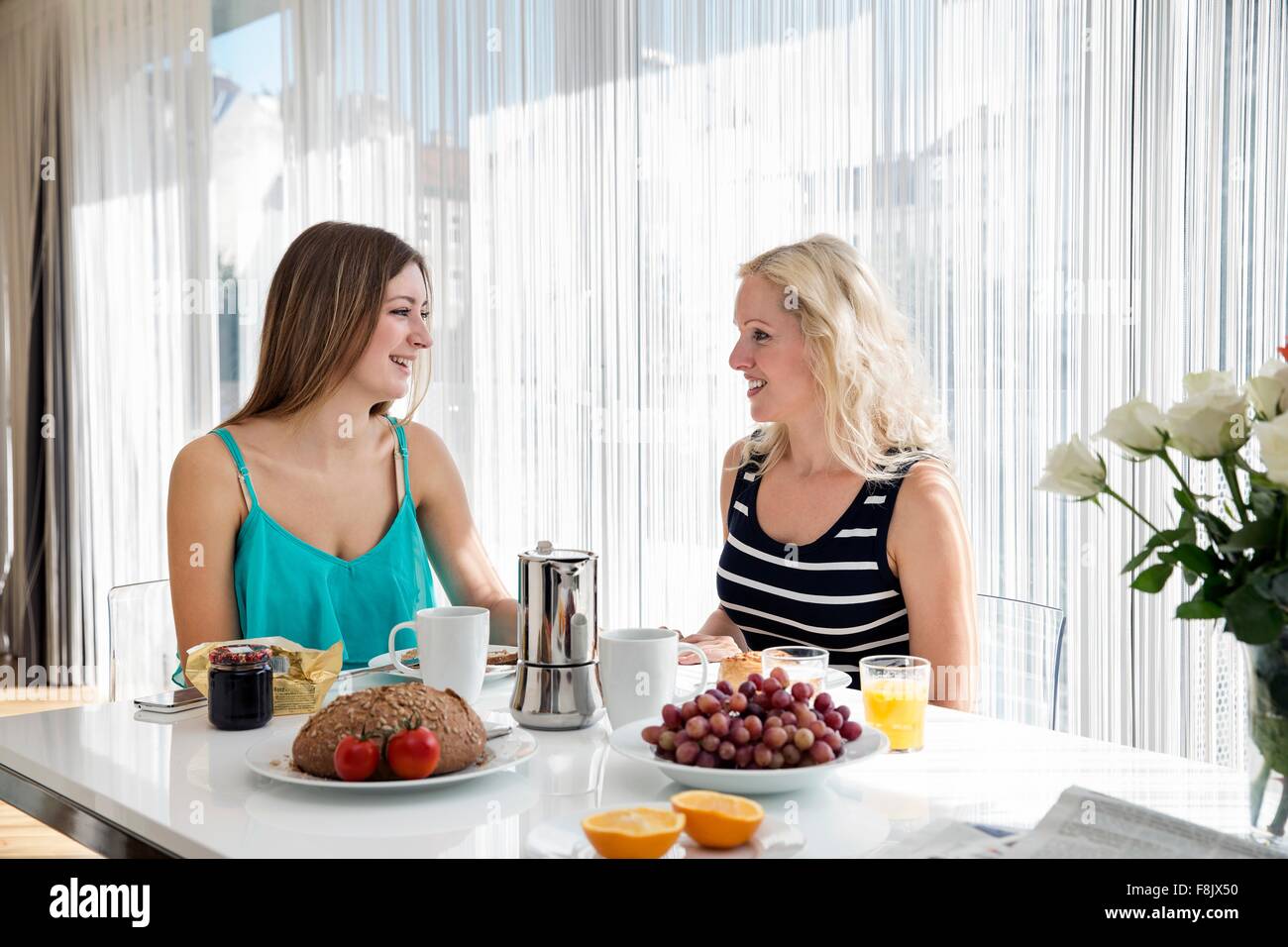 Les femmes assis à table à manger bénéficiant d''un petit-déjeuner ensemble, face à face, smiling Banque D'Images