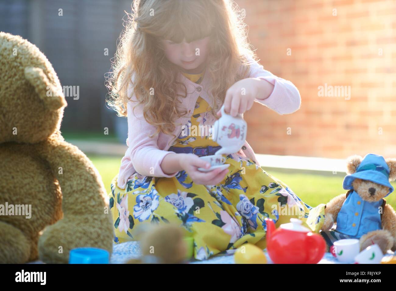 Girl teddy bear picnic dans jardin pouring tea Banque D'Images