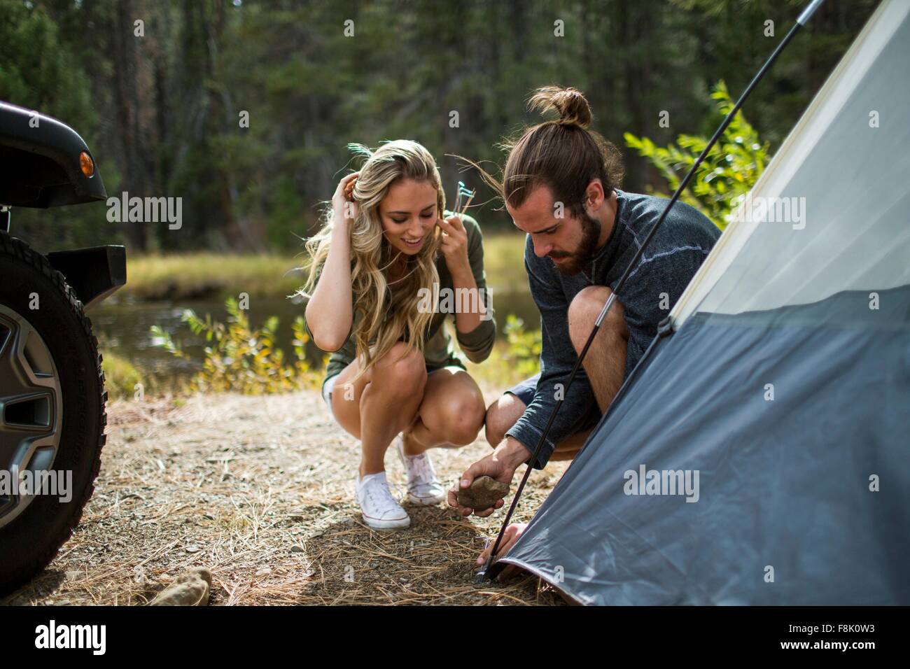 Jeune couple mise en place tente sur Riverside Forest, Lake Tahoe, Nevada, USA Banque D'Images