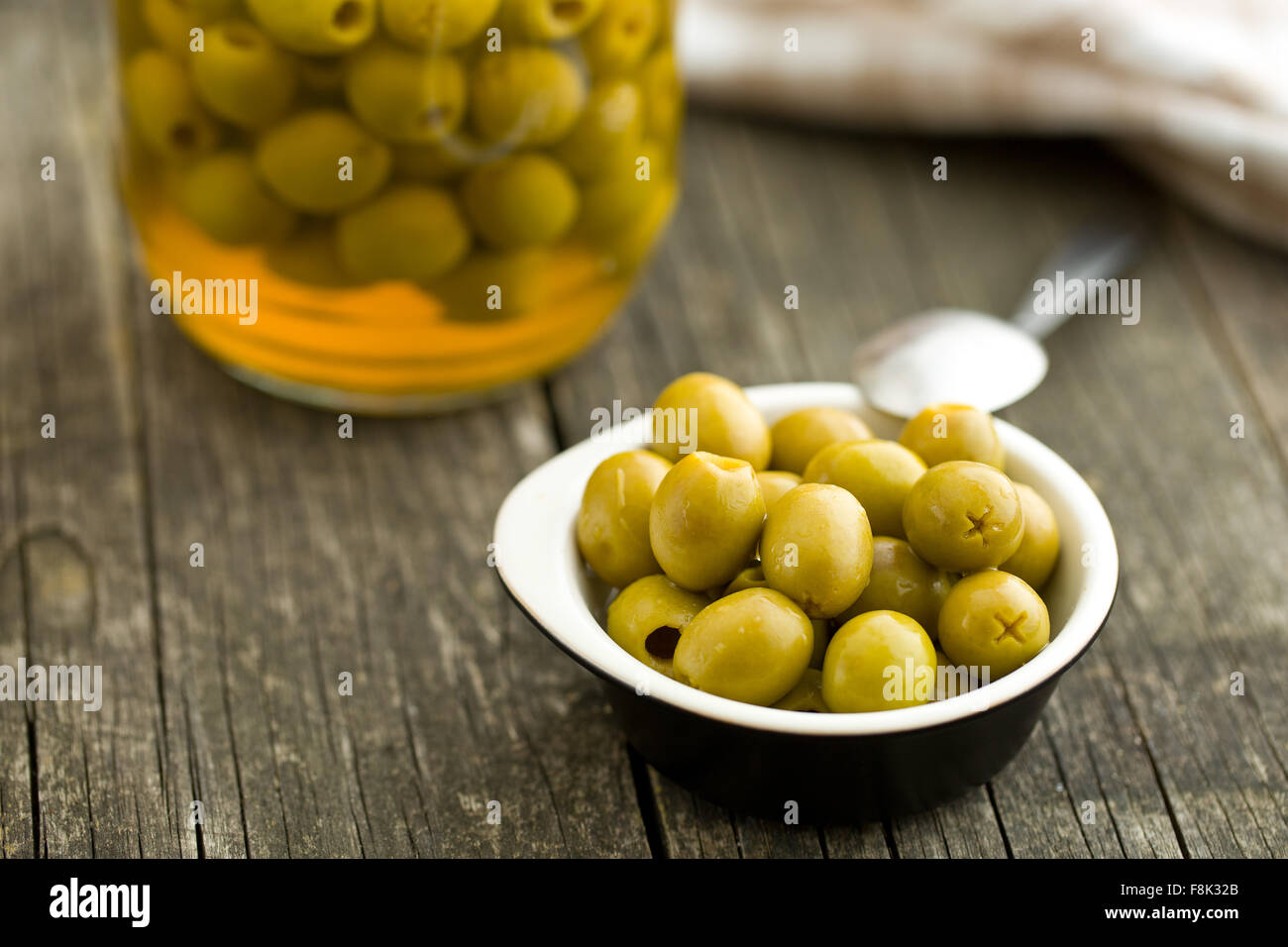 Olives vertes dénoyautées dans un bol sur la table en bois Banque D'Images