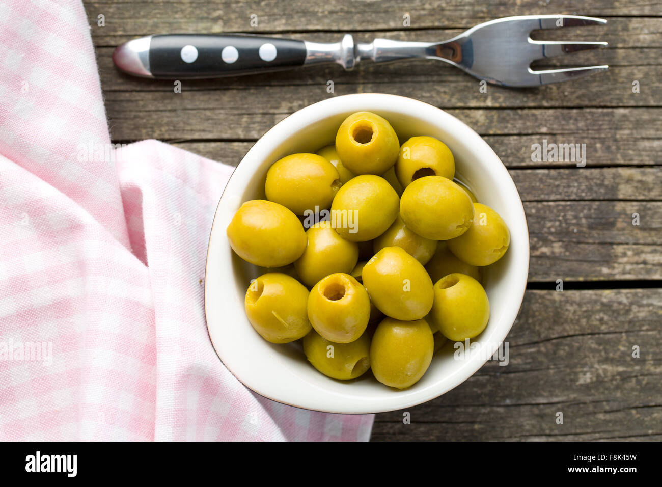 Olives vertes dénoyautées dans un bol sur la table en bois Banque D'Images