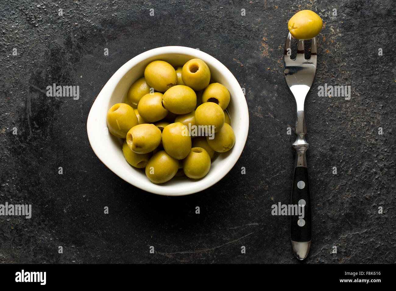 Olives vertes dénoyautées dans un bol sur le tableau noir Banque D'Images