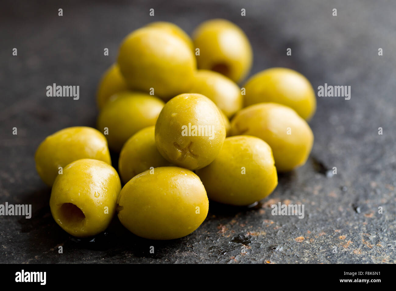 Olives vertes dénoyautées sur tableau noir Banque D'Images