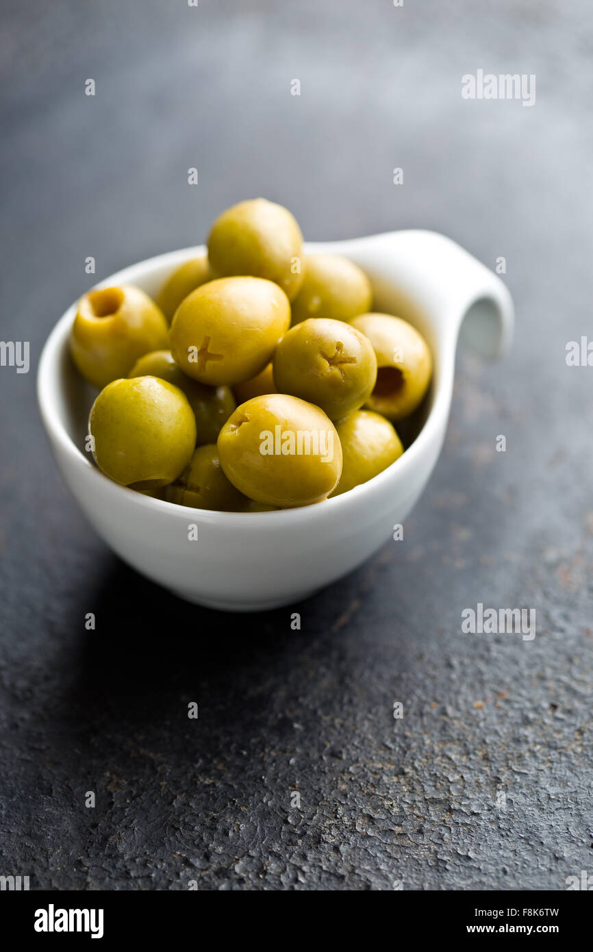 Olives vertes dénoyautées dans un bol sur le tableau noir Banque D'Images