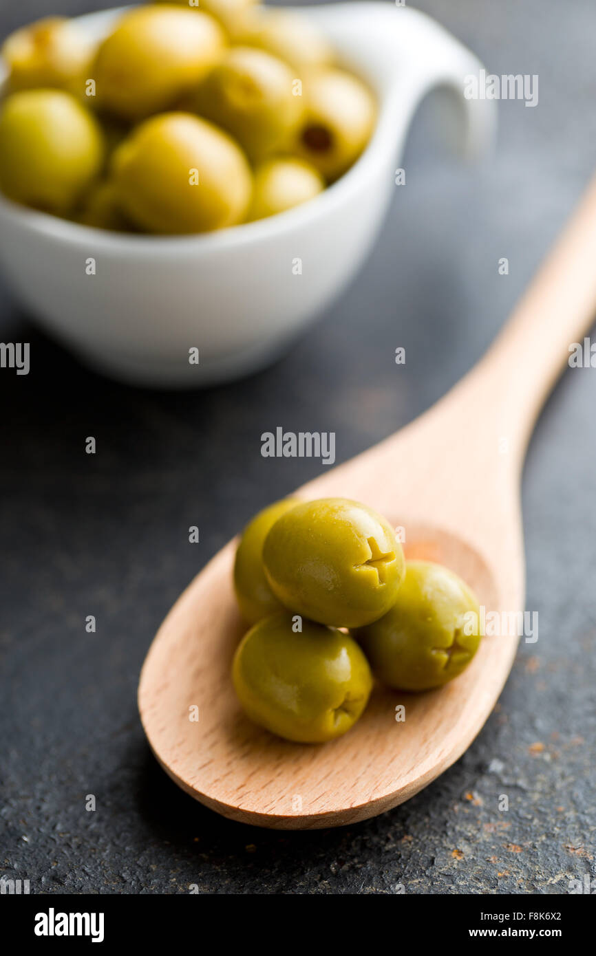 Olives vertes dénoyautées sur cuillère en bois Banque D'Images