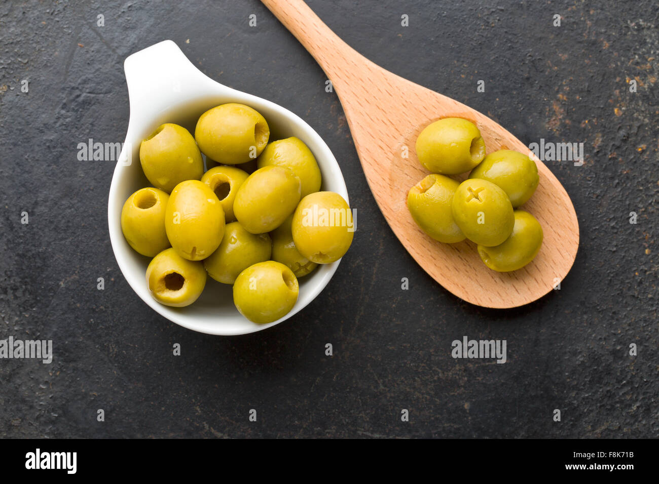 Olives vertes dénoyautées dans un bol sur le tableau noir Banque D'Images