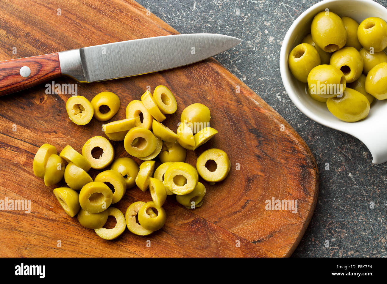 Olives vertes en rondelles sur une planche à découper Banque D'Images