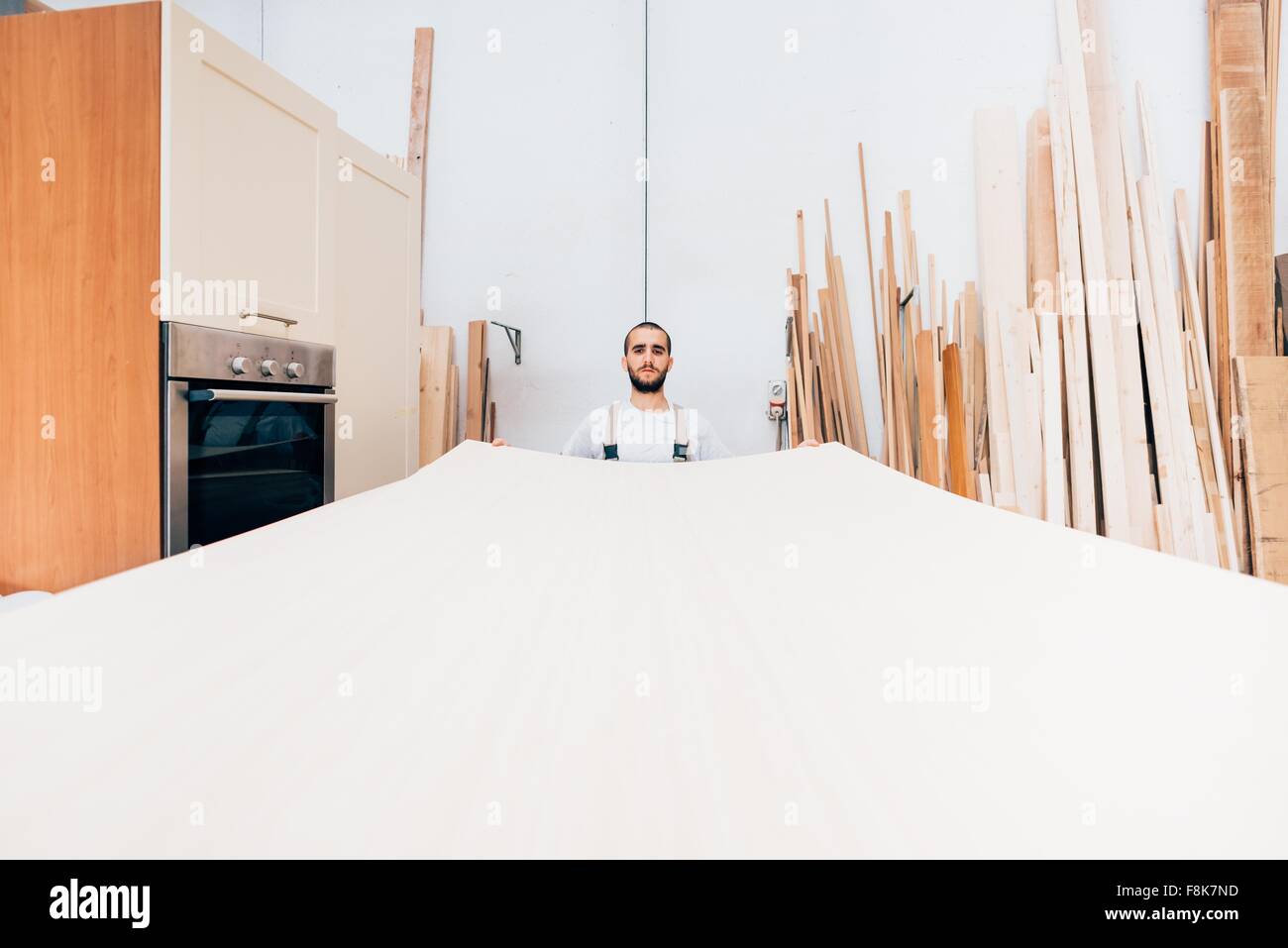 Carpenter avec grande feuille de bois dans l'atelier Banque D'Images