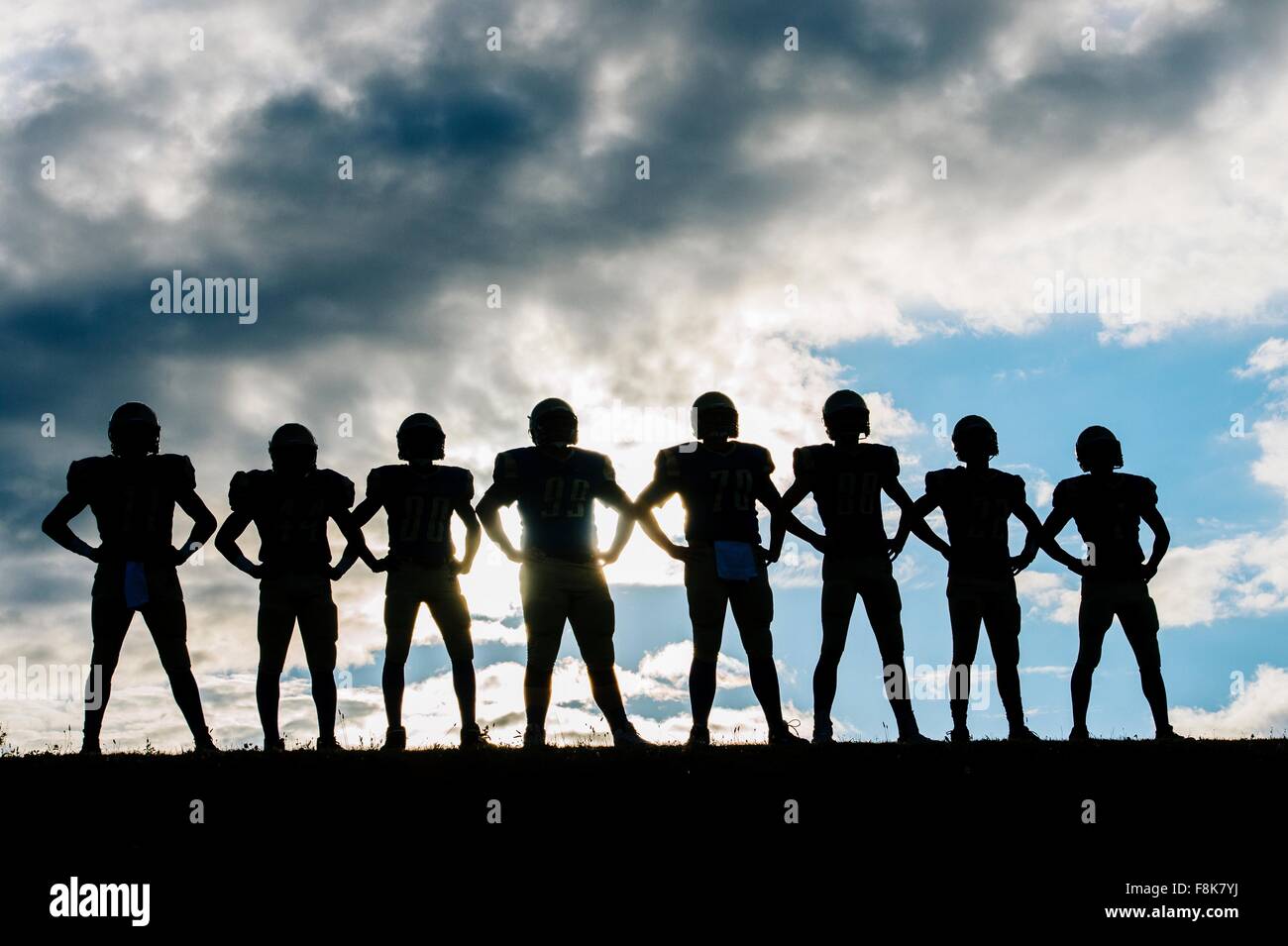Silhouette de groupe de jeunes joueurs de football américain, l'article en ligne, les mains sur les hanches Banque D'Images