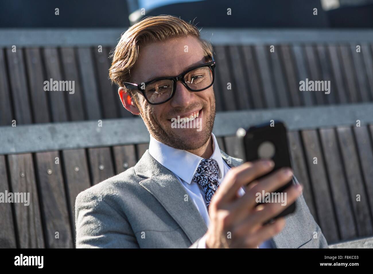 Young businessman reading text smartphone en ville Banque D'Images