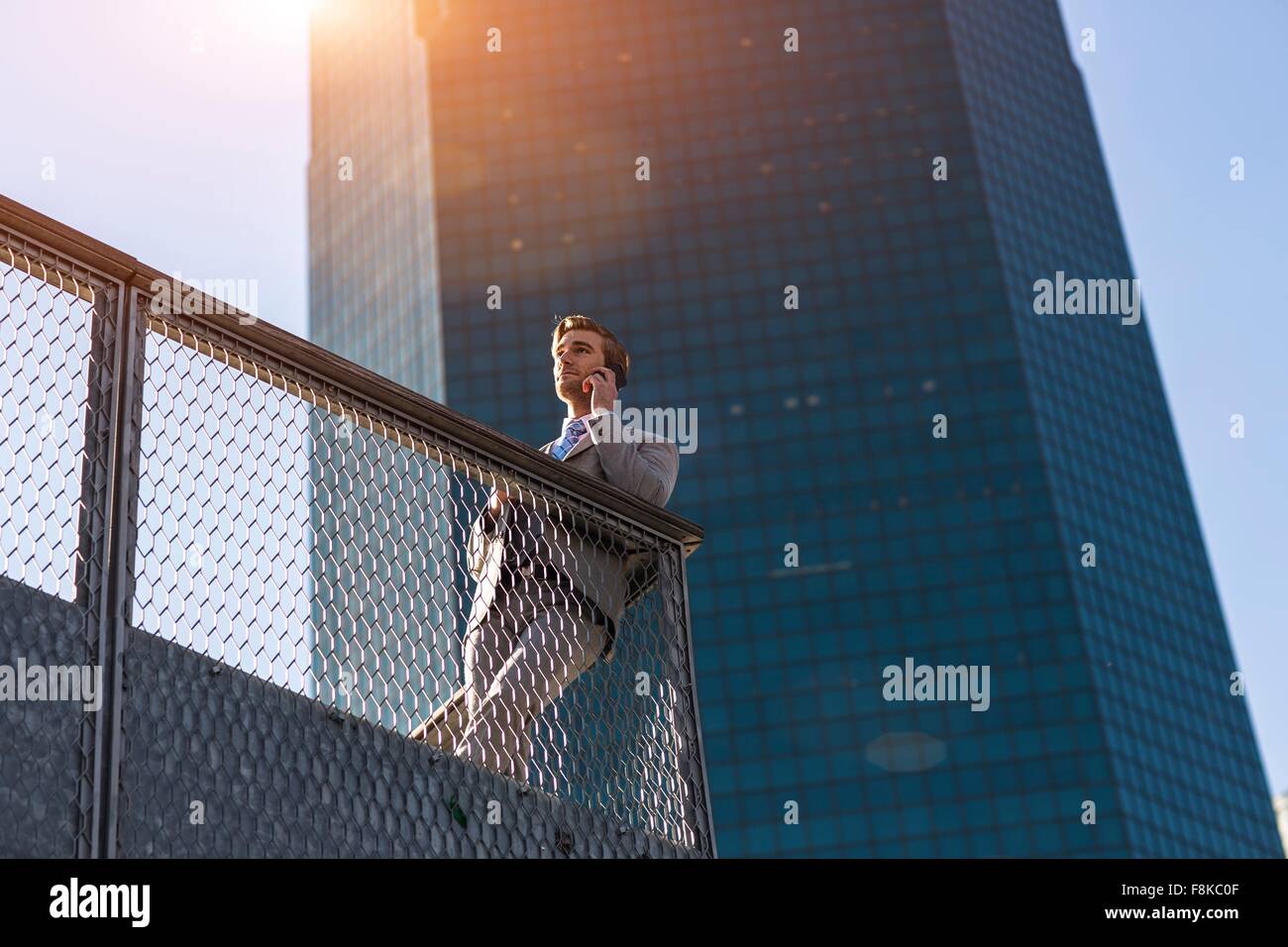 Low angle view of young businessman chatting on smartphone sur balcon-ville, New York, USA Banque D'Images