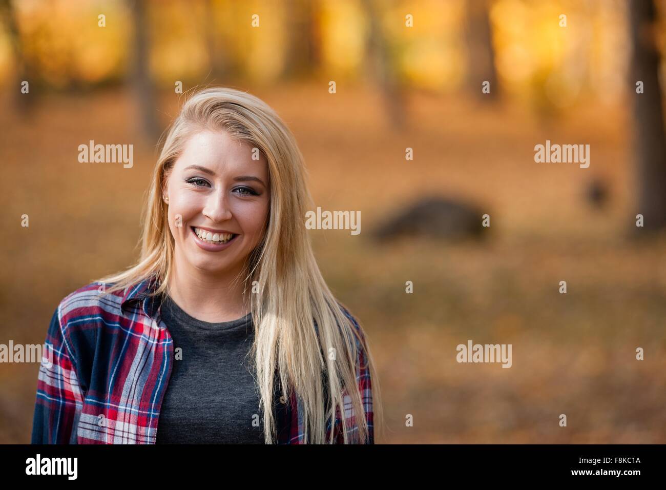 Tête et épaule portrait de jeune femme avec de longs cheveux blonds en forêt d'automne Banque D'Images