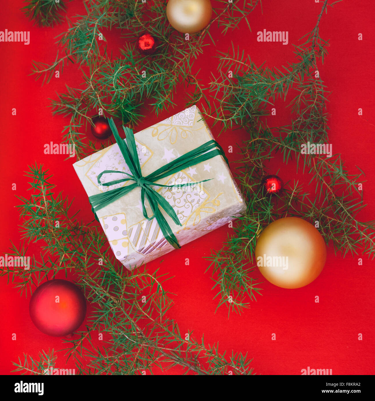 Hand wrapped christmas gift avec ruban vert à fond rouge avec des jouets de Noël Banque D'Images