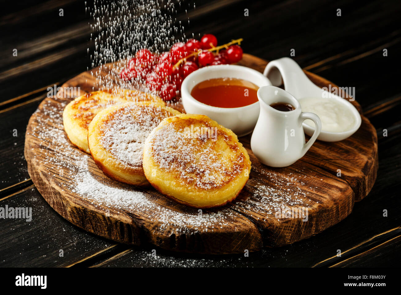 Crêpes au fromage cottage maison syrniki russe avec des sauces sucrées sur fond de bois Banque D'Images