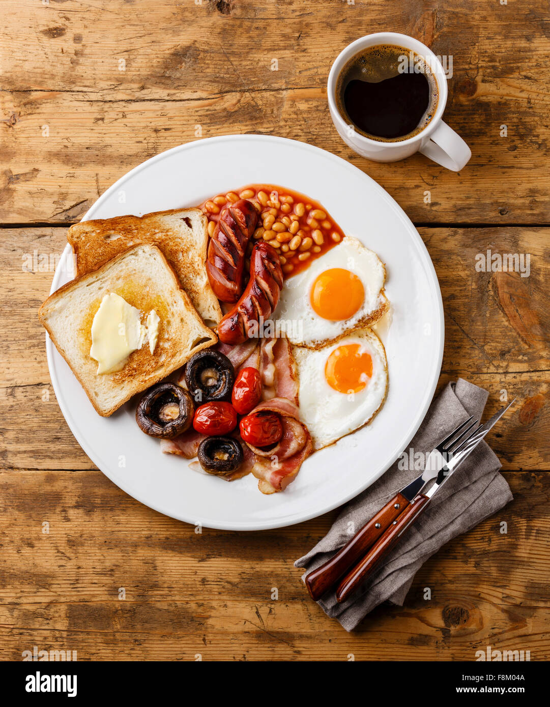 Le petit déjeuner anglais complet avec les œufs, saucisses, bacon, haricots, pain grillé, tomates et champignons sur fond de bois Banque D'Images