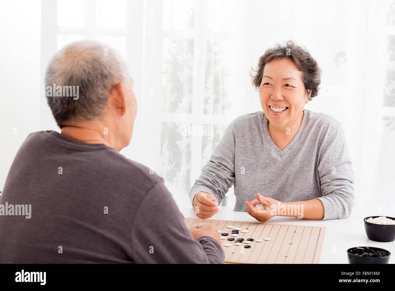 Happy asian senior couple jouant aux échecs dans la salle de séjour Banque D'Images
