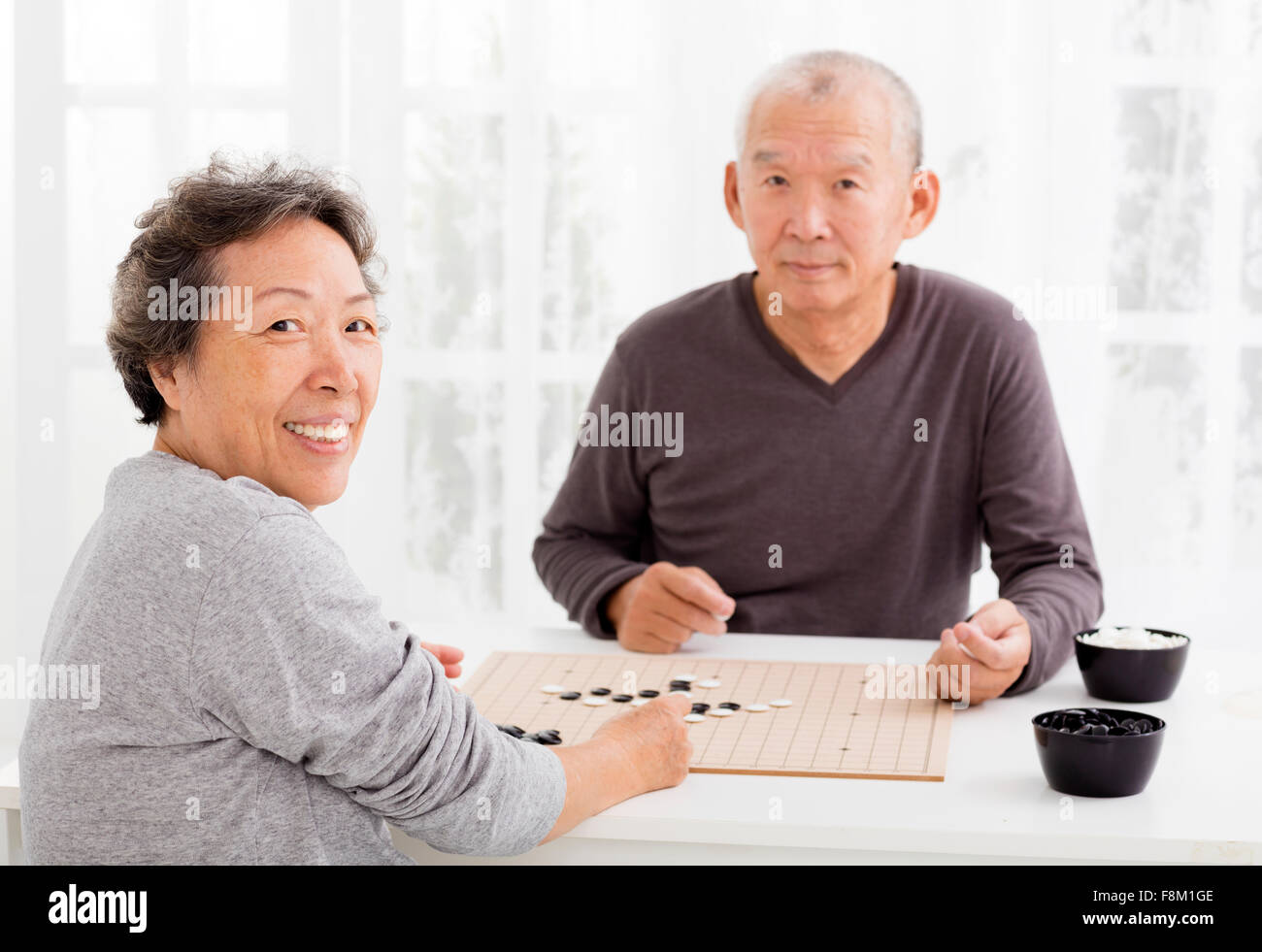 Happy asian senior couple jouant aux échecs dans la salle de séjour Banque D'Images