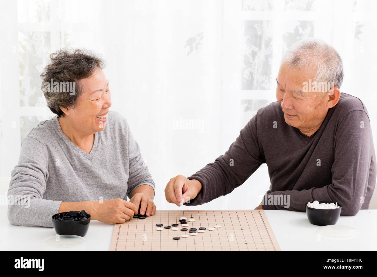 Happy asian senior couple jouant aux échecs dans la salle de séjour Banque D'Images