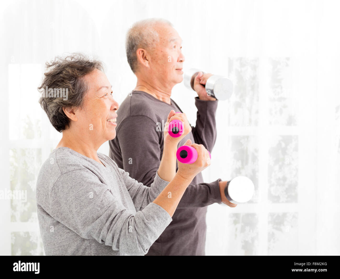 Happy senior couple exercising with dumbbells Banque D'Images