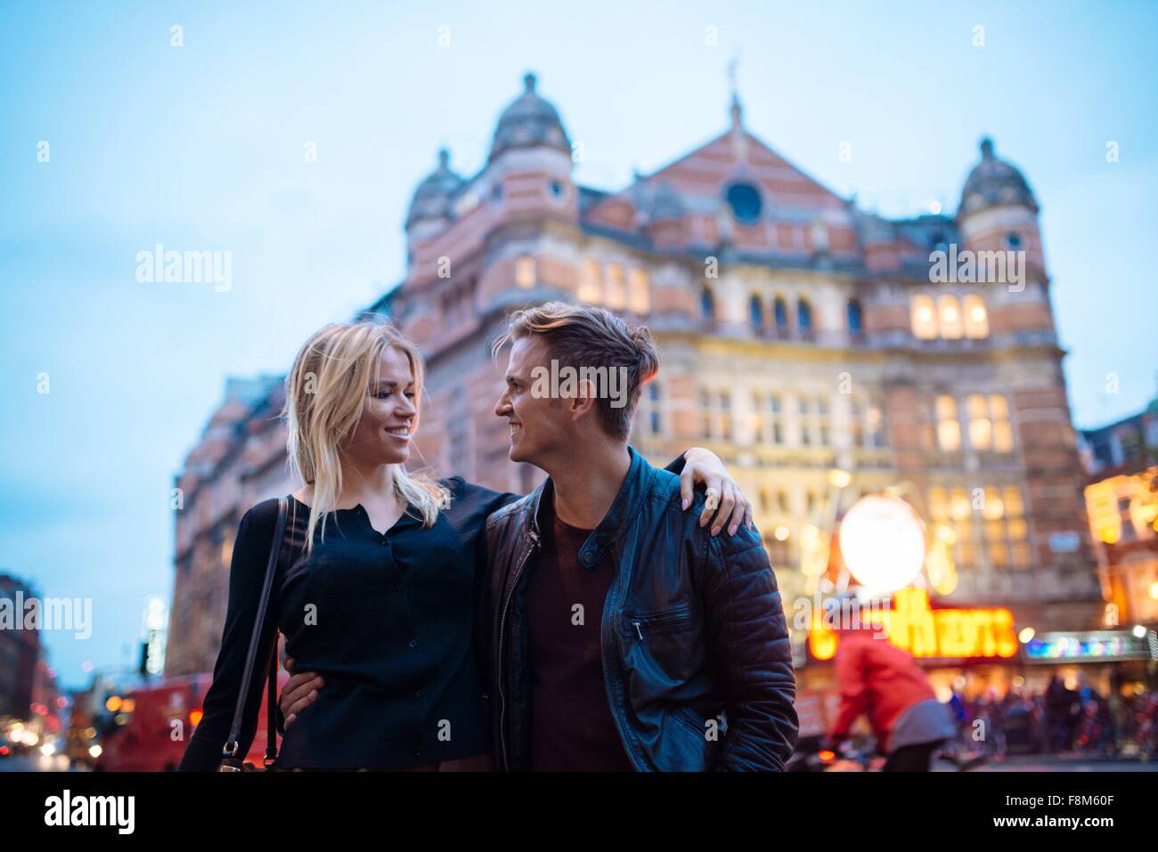 Jeune couple strolling on city street at night, London, England, UK Banque D'Images